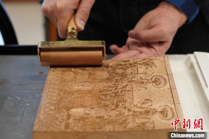 圖為徐晉林工作室工作人員正在給雕好壁畫的版面滾油墨?！【琶赖┰?　攝