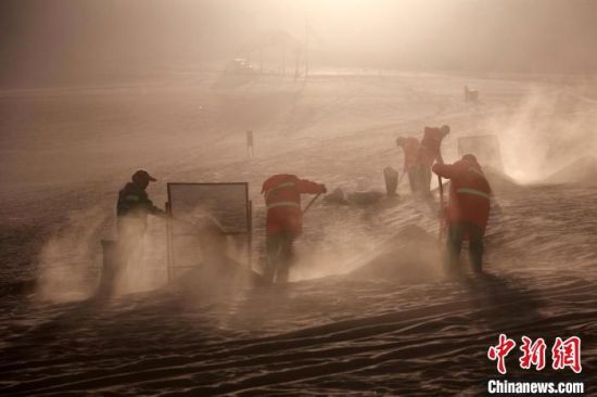 圖為敦煌市鳴沙山月牙泉景區(qū)“駱駝保姆”清理駱駝糞便。　張曉亮 攝