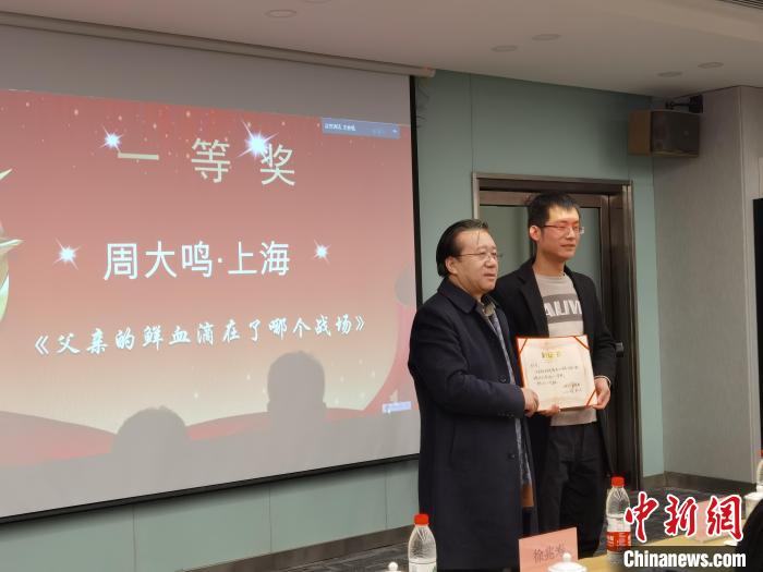 圖為作家、西北師范大學(xué)新聞與傳媒學(xué)院院長(zhǎng)徐兆壽頒發(fā)一等獎(jiǎng)證書(shū)，代領(lǐng)獎(jiǎng)?wù)呱吓_(tái)領(lǐng)獎(jiǎng)?！钅?攝