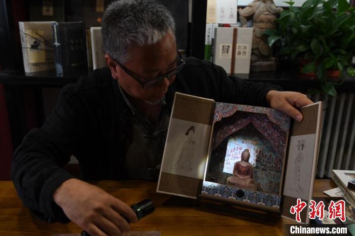 圖為讀者出版集團(tuán)讀者晉林工作室獨(dú)立出品人徐晉林，展示互動(dòng)性強(qiáng)的敦煌題材手工書。(資料圖) 楊艷敏 攝