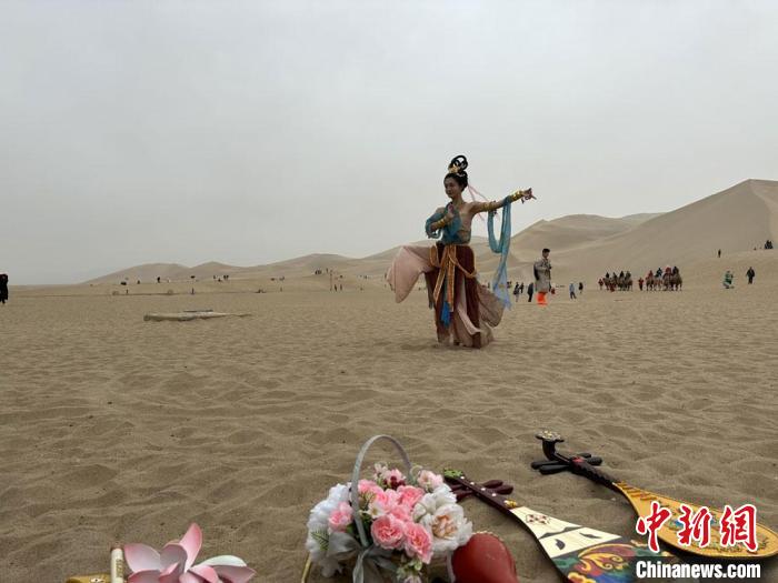 圖為2023年4月底，敦煌大漠“逐舞者”奧楠在鳴沙山月牙泉景區(qū)視頻直播敦煌舞?！●T志軍 攝