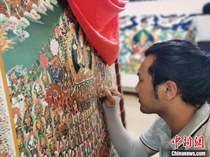 圖為更登才讓的徒弟繪畫唐卡?！?zhí)砀?攝