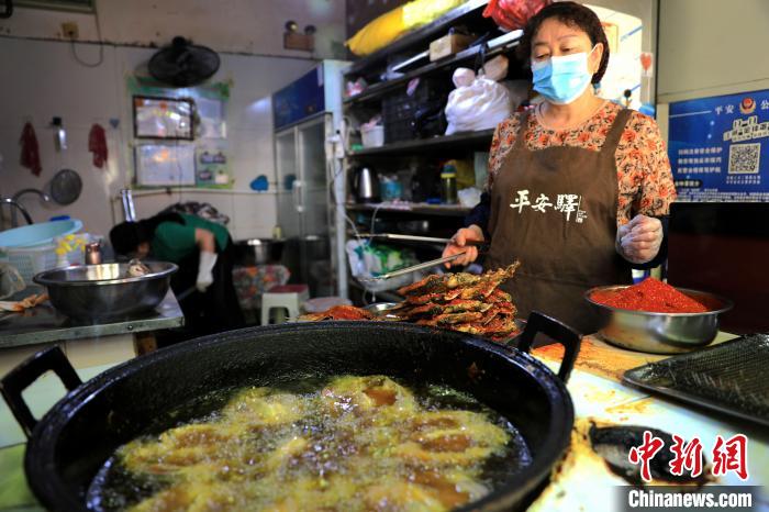 圖為平安驛·河湟民俗文化體驗地內(nèi)的商戶炸干板魚?！⊙Φ?攝