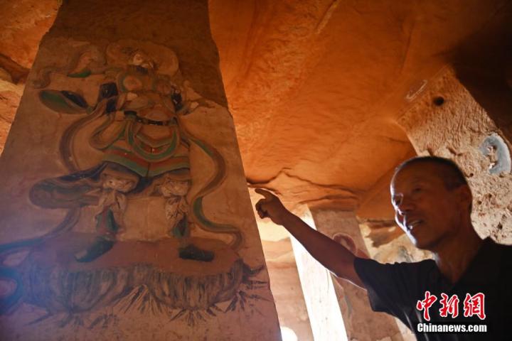 7月15日，甘肅省平?jīng)鍪袥艽h百里石窟長廊羅漢洞石窟內，該窟文保員郭建平介紹窟內石刻彩繪壁畫。郭建平家中三代人曾自發(fā)保護羅漢洞石窟。羅漢洞石窟遺存40余個窟龕，以北魏至清代風格為主。中新社記者 李亞龍 攝</p>
<p>